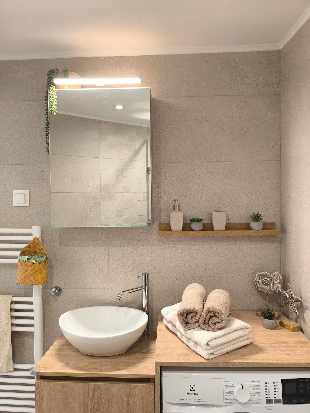 Badezimmer mit Handtuchheizkörper, Waschbecken mit Spiegelschrank und Waschmaschine